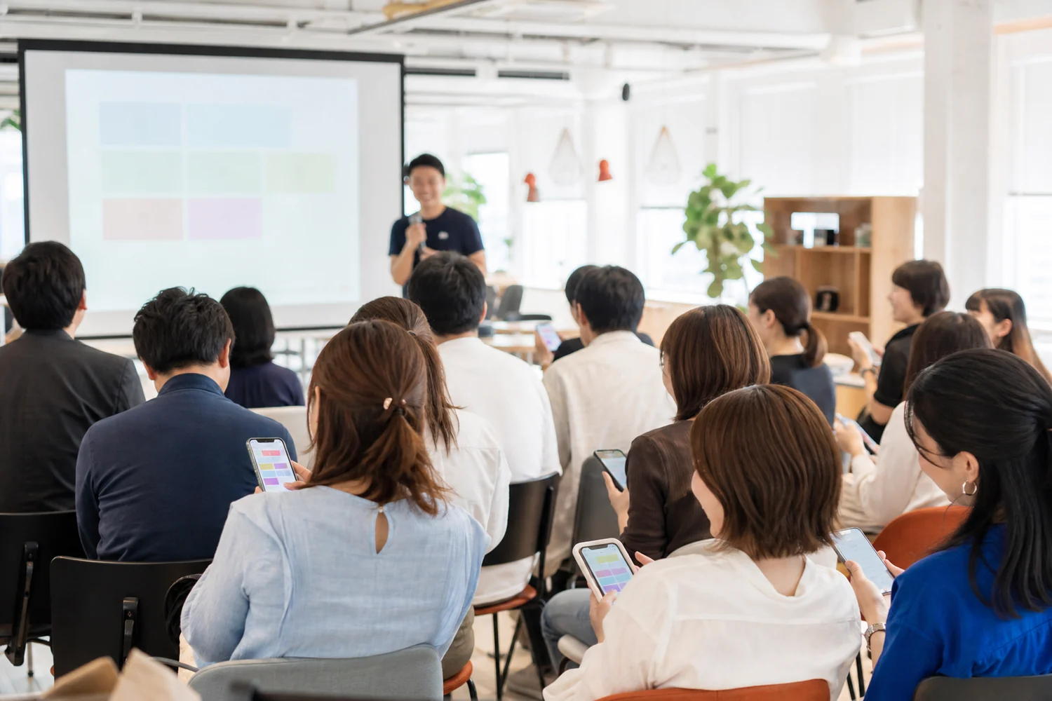 社内イベントでスマートフォンを使ったクイズに参加する社員